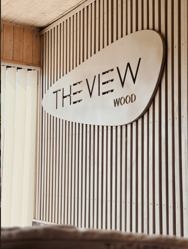 Shenja e gdhendur THE VIEW WOOD mbi murin me llata druri
